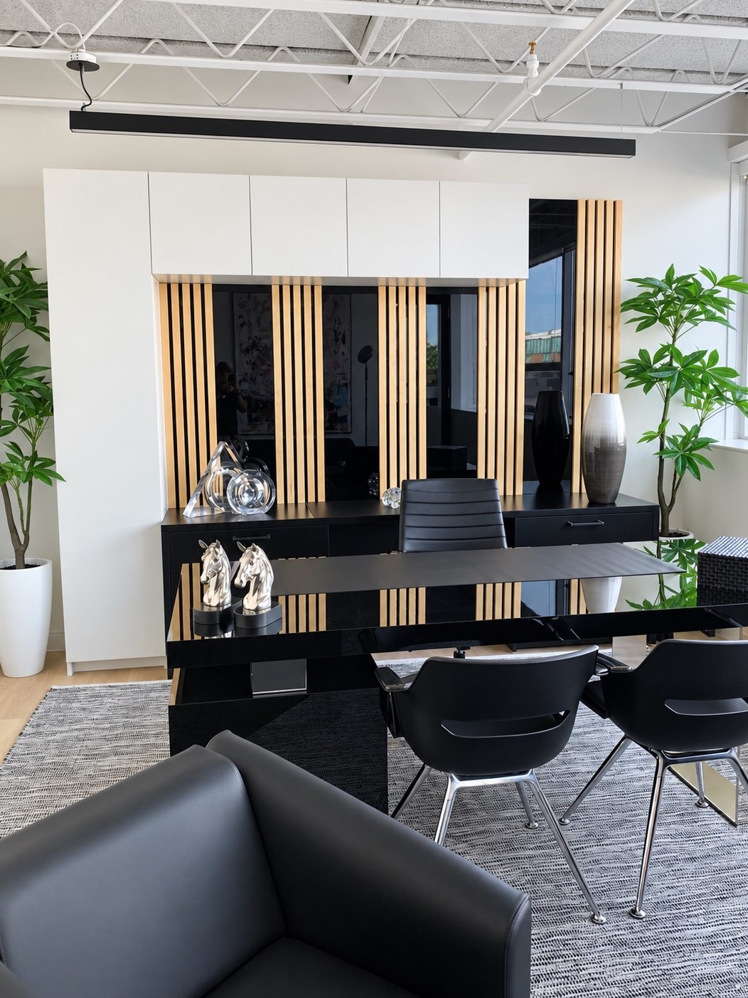 CNFL executive office with a built-in white cabinet over a black credenza, vertical wood slat panelling, a black lacquer desk and potted plants