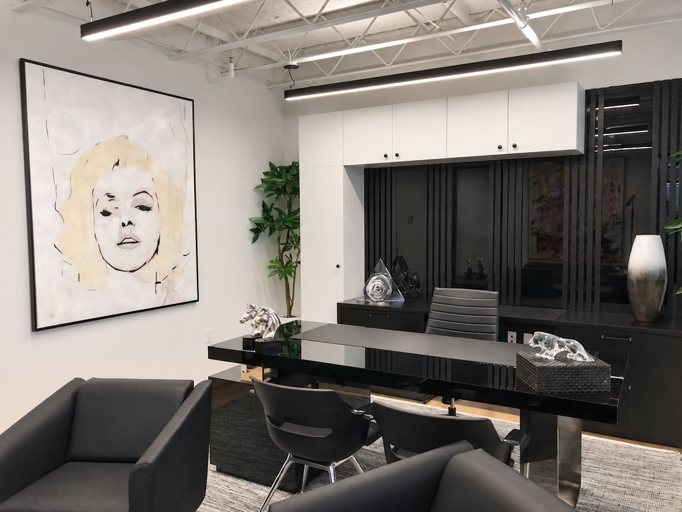 Executive office with white upper cabinets over black slat panelling, a black lacquer desk and credenza, and a large framed portrait painting