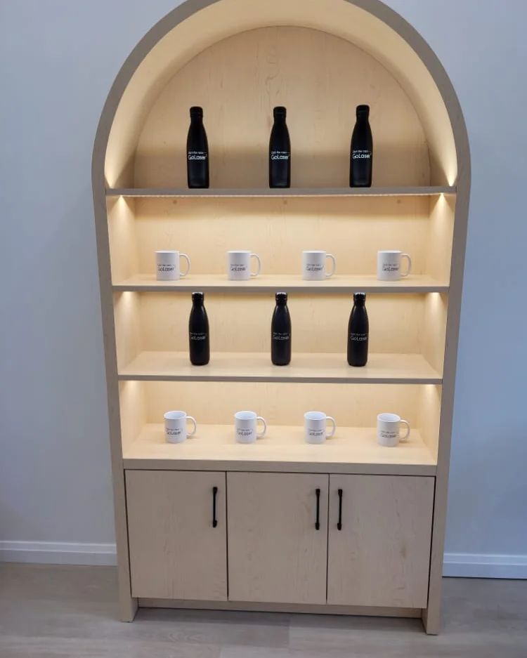 GoLaser clinic — custom arched maple display cabinet with integrated LED shelf lighting built by Leewood Finishing