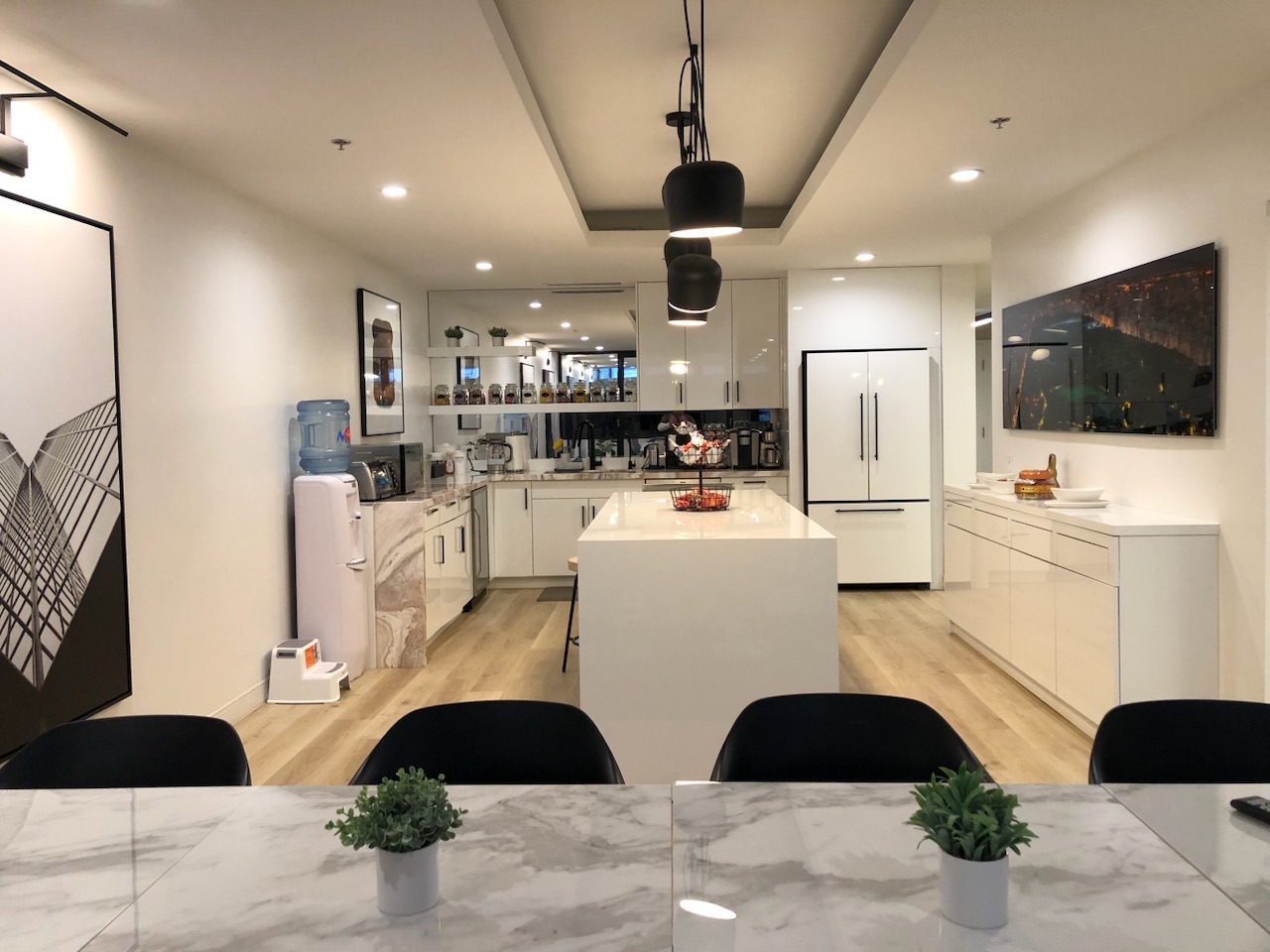 Modern open-plan kitchen with full-height white cabinetry, marble island, and custom millwork throughout