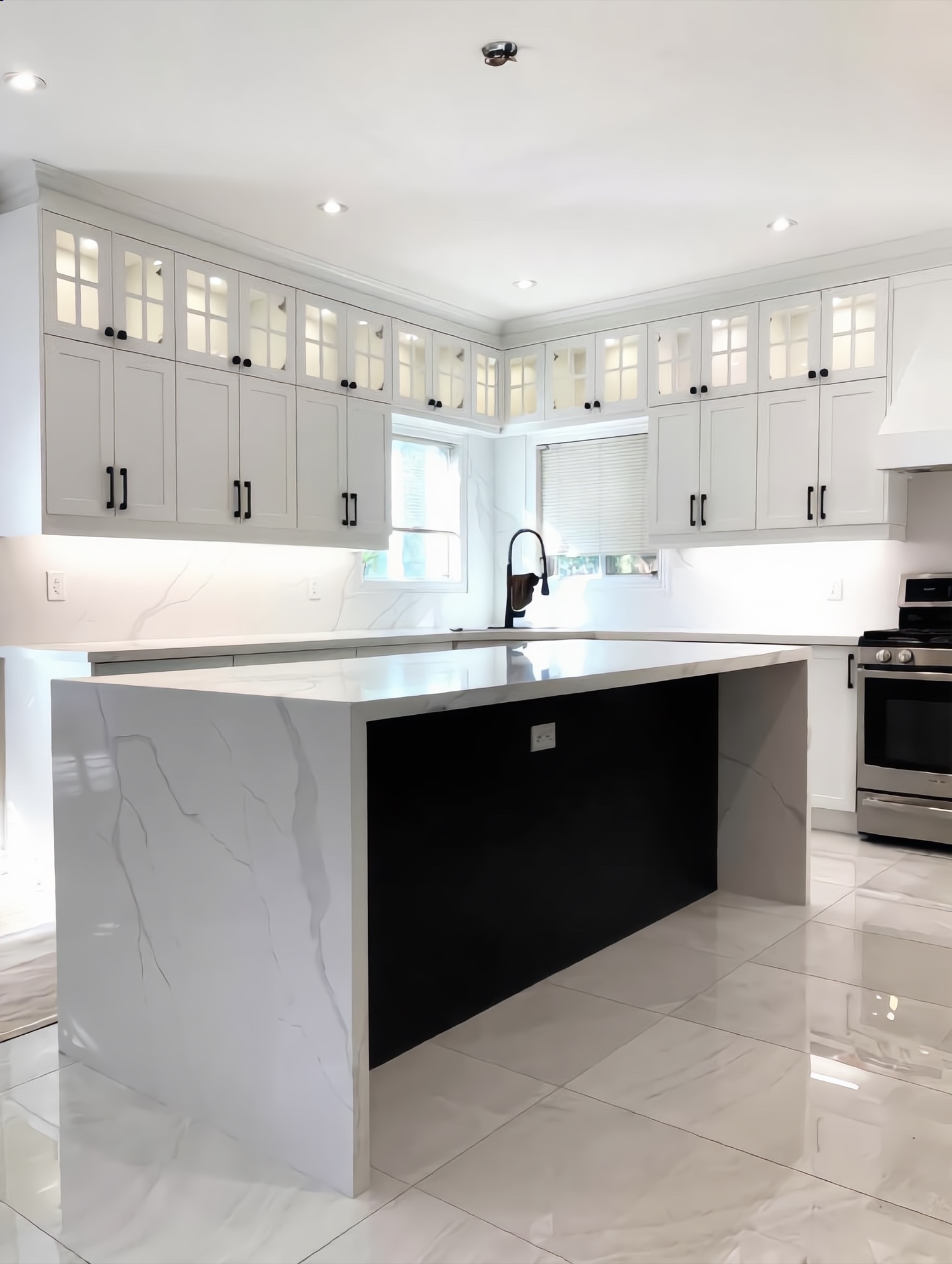 Custom white kitchen with marble waterfall island and black hardware built by Leewood Finishing