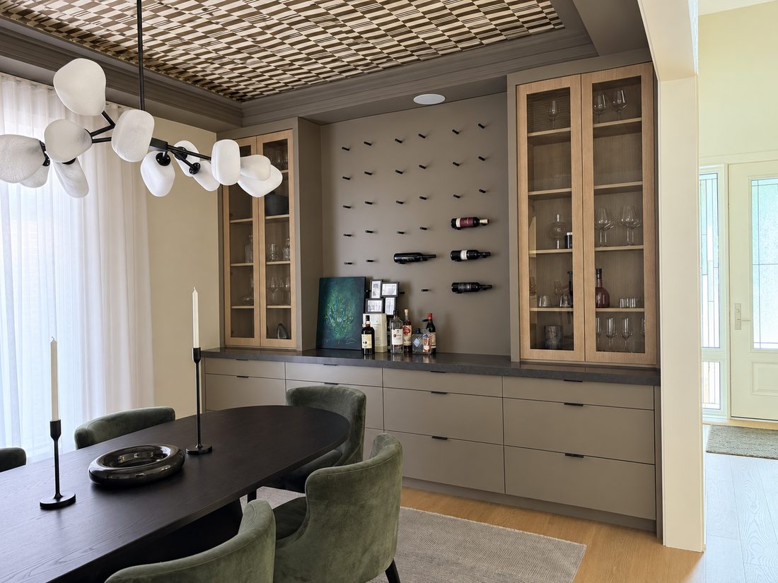 Dining room servery in white oak and grey lacquer with glass-front display cabinets, a dark stone counter, and a wall-mounted wine rack between them