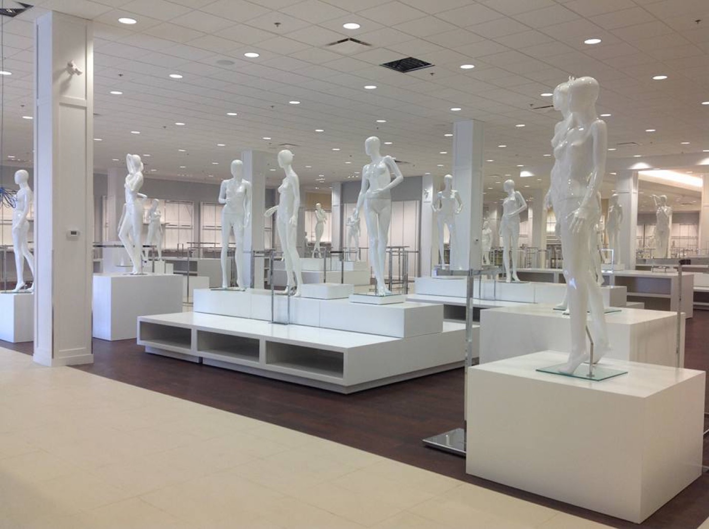 Large-format retail space with custom white lacquer display platforms and millwork pedestals